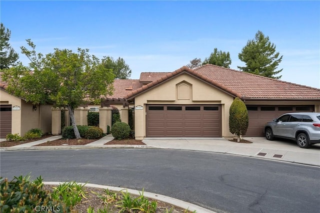 view of front of home featuring a garage, concrete driveway, a tile roof, and stucco siding