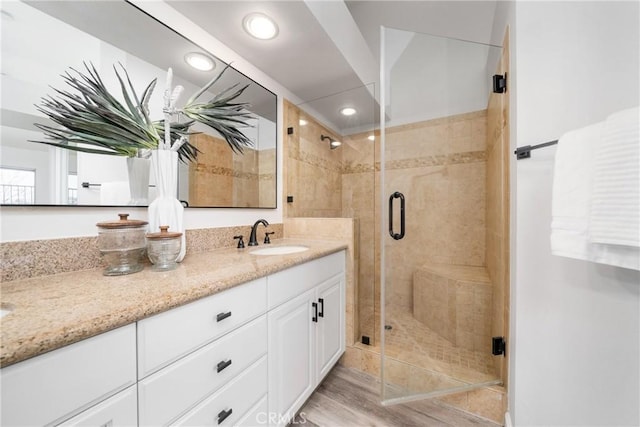 bathroom featuring a stall shower, wood finished floors, vanity, and recessed lighting