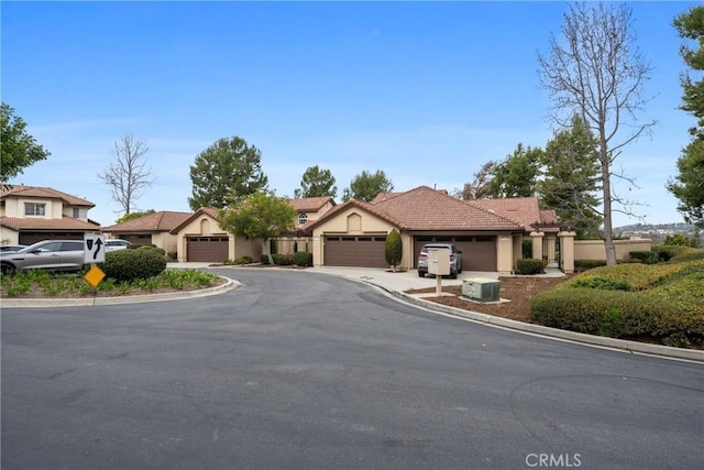 view of front facade featuring a tile roof, driveway, an attached garage, and stucco siding