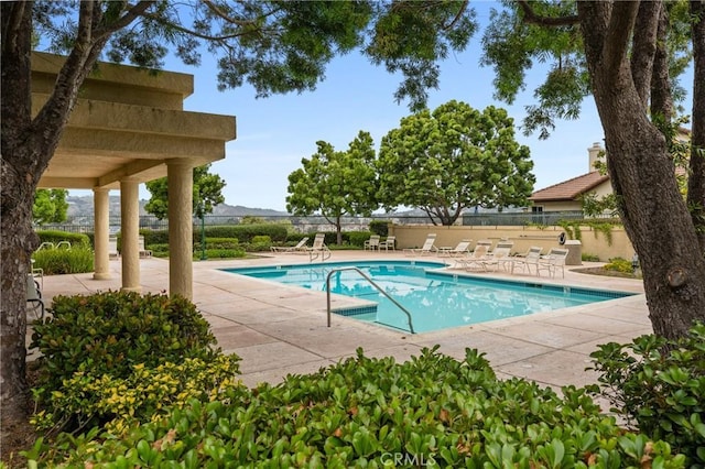 community pool with a patio and fence