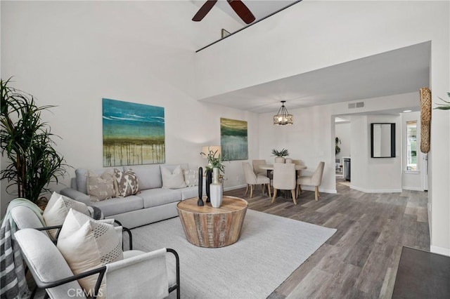 living room with a ceiling fan, visible vents, baseboards, and wood finished floors