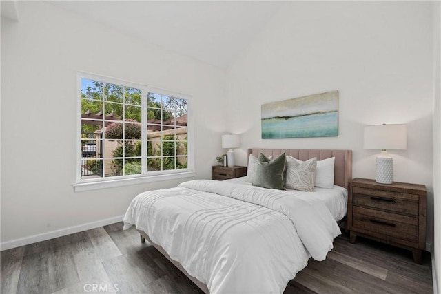 bedroom with lofted ceiling, wood finished floors, and baseboards