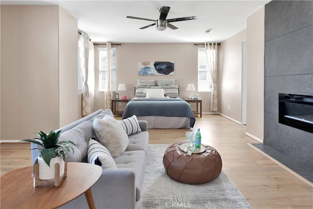 bedroom featuring light wood-style floors, a tile fireplace, visible vents, and multiple windows