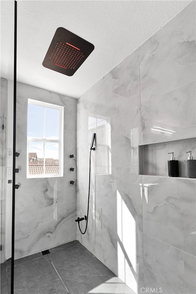 bathroom with a marble finish shower and a textured ceiling