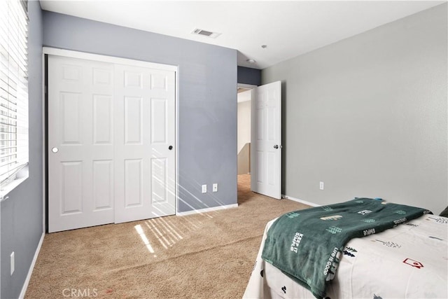 carpeted bedroom featuring baseboards, visible vents, and a closet