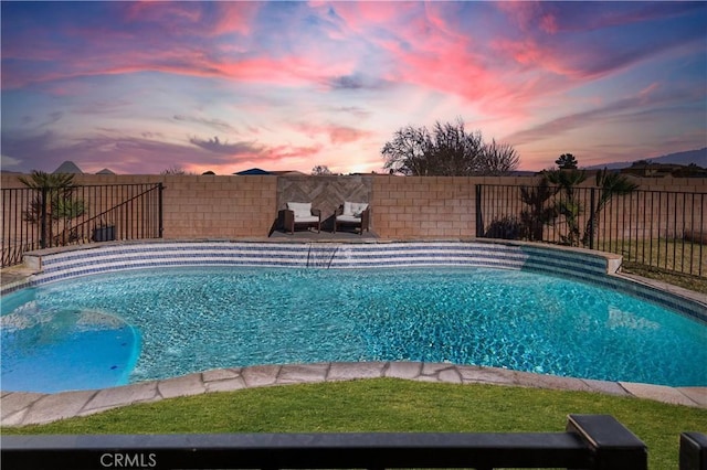 pool at dusk featuring a fenced in pool and a fenced backyard