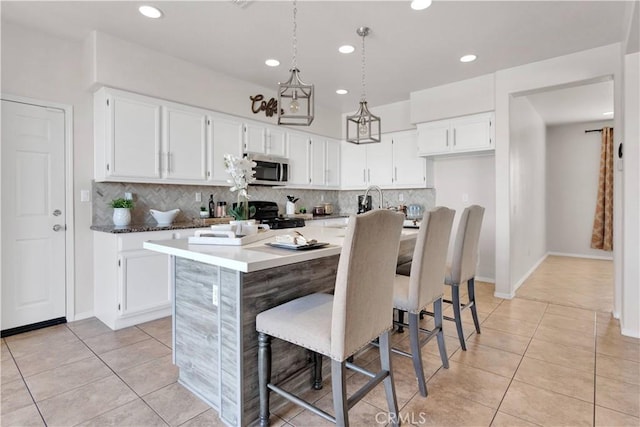 kitchen with light tile patterned floors, stainless steel microwave, white cabinets, and decorative backsplash