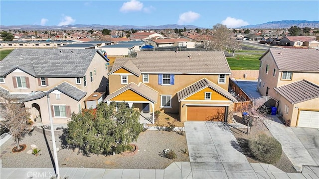 view of front facade with a residential view, concrete driveway, a mountain view, and stucco siding