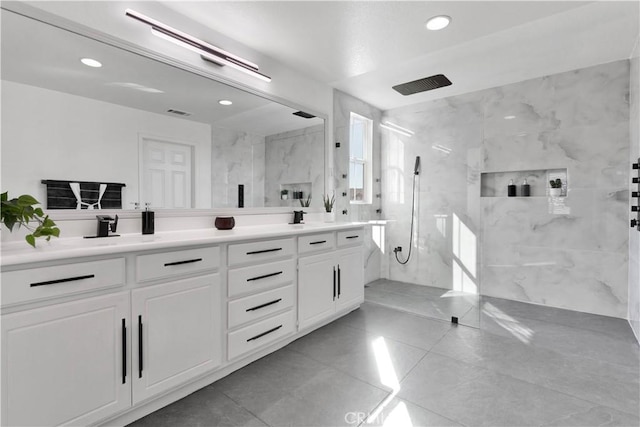 bathroom featuring a sink, double vanity, a marble finish shower, and recessed lighting