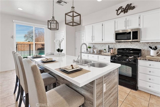 kitchen featuring black range with gas cooktop, a sink, visible vents, tasteful backsplash, and stainless steel microwave