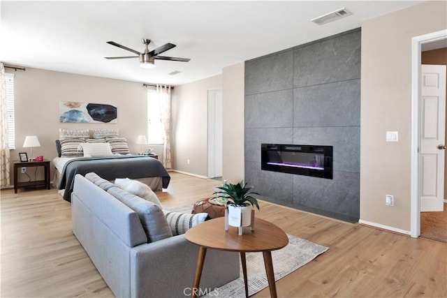 bedroom with light wood-type flooring, a fireplace, visible vents, and baseboards