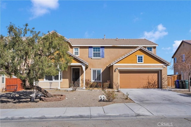 traditional-style house featuring an attached garage, covered porch, fence, driveway, and stucco siding