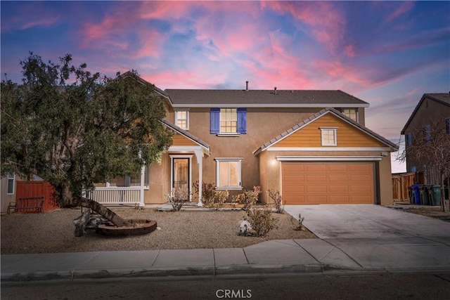 traditional-style house featuring driveway, an attached garage, fence, and stucco siding