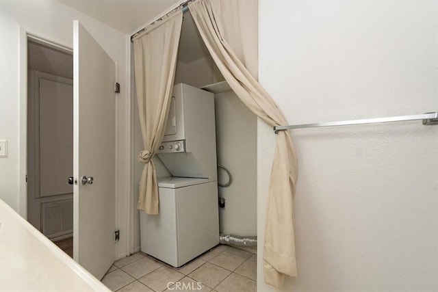 laundry room featuring light tile patterned floors, stacked washer and dryer, and laundry area