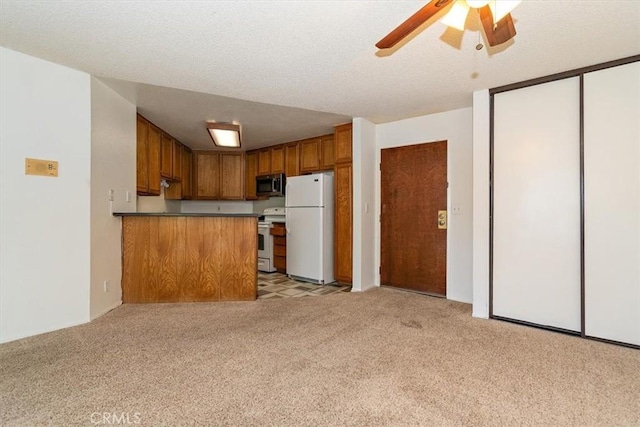 kitchen featuring light colored carpet, brown cabinetry, open floor plan, white appliances, and a peninsula