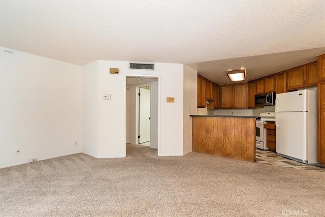 kitchen featuring brown cabinets, light colored carpet, white appliances, and visible vents