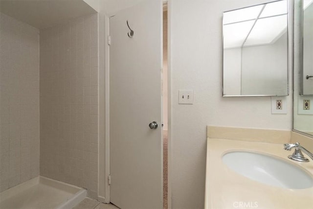 full bath featuring a tile shower and vanity