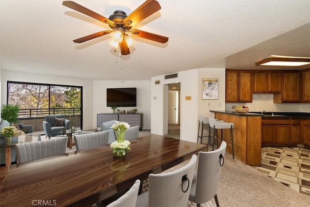 dining room with a textured ceiling, visible vents, and a ceiling fan