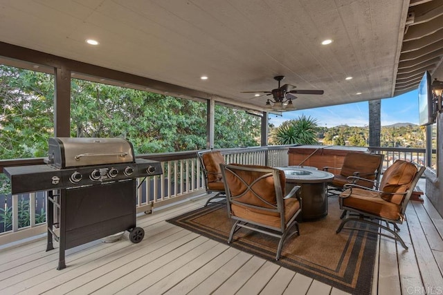 wooden deck with ceiling fan, a fire pit, and grilling area