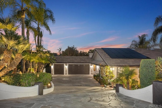 view of front of property with concrete driveway, roof mounted solar panels, and an attached garage