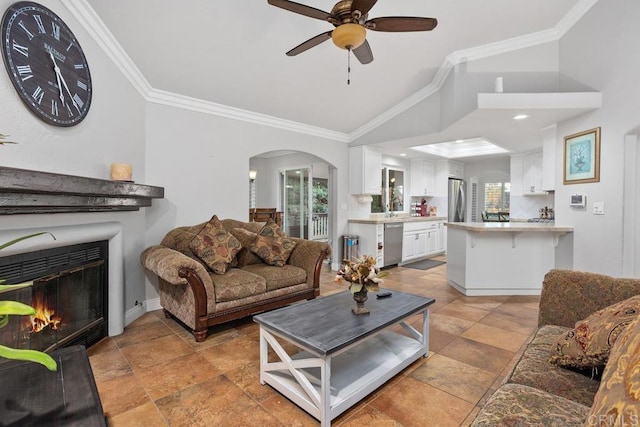 living area featuring lofted ceiling, arched walkways, a ceiling fan, and ornamental molding