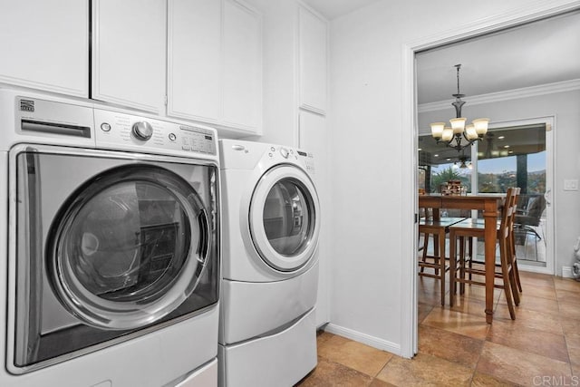 laundry room with a notable chandelier, baseboards, ornamental molding, cabinet space, and washing machine and clothes dryer