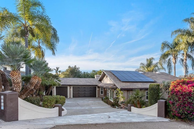 view of front of house featuring driveway, solar panels, a tiled roof, an attached garage, and stucco siding