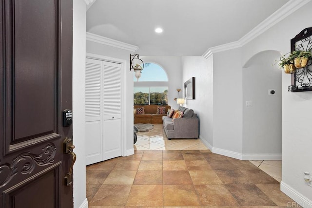 corridor with arched walkways, light tile patterned flooring, crown molding, and baseboards