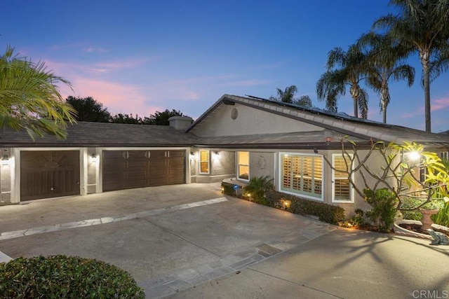 ranch-style home with a garage, driveway, and stucco siding