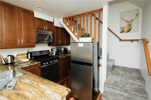 kitchen featuring appliances with stainless steel finishes, a sink, and light stone countertops