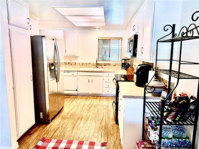 kitchen featuring appliances with stainless steel finishes, light countertops, light wood-type flooring, white cabinetry, and a sink