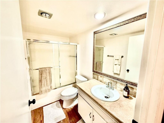 full bathroom featuring tasteful backsplash, toilet, combined bath / shower with glass door, vanity, and wood finished floors