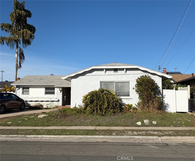 bungalow-style house featuring fence and stucco siding