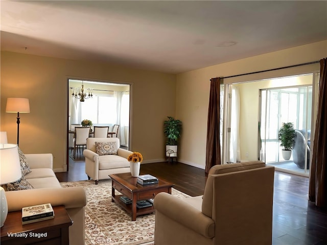 living area with baseboards, a notable chandelier, and wood finished floors