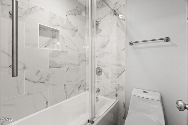 bathroom featuring toilet and shower / bath combination with glass door