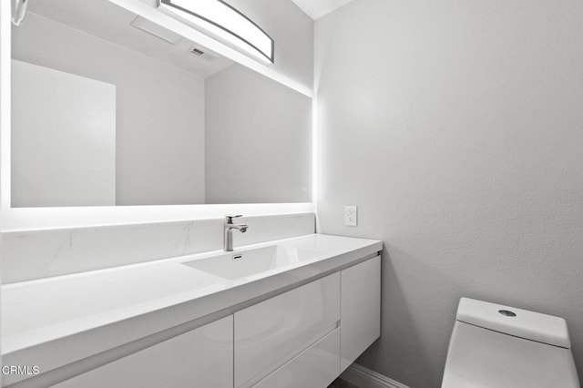 half bathroom with baseboards, visible vents, a textured wall, toilet, and vanity