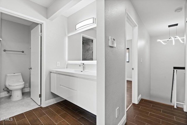 full bath featuring toilet, vanity, baseboards, and wood finish floors