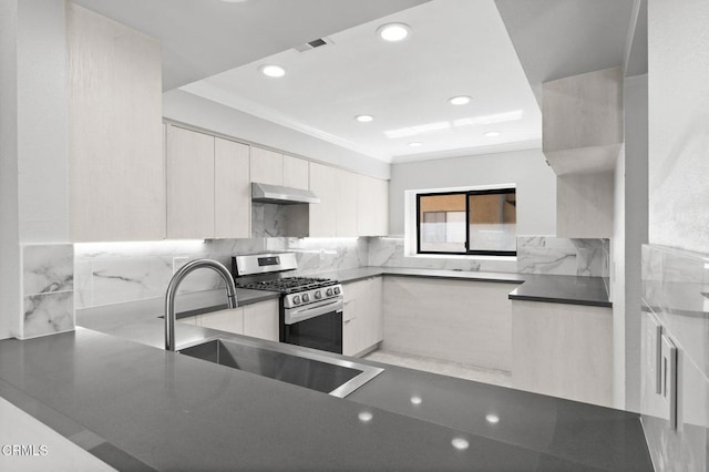 kitchen featuring dark countertops, backsplash, modern cabinets, under cabinet range hood, and gas range