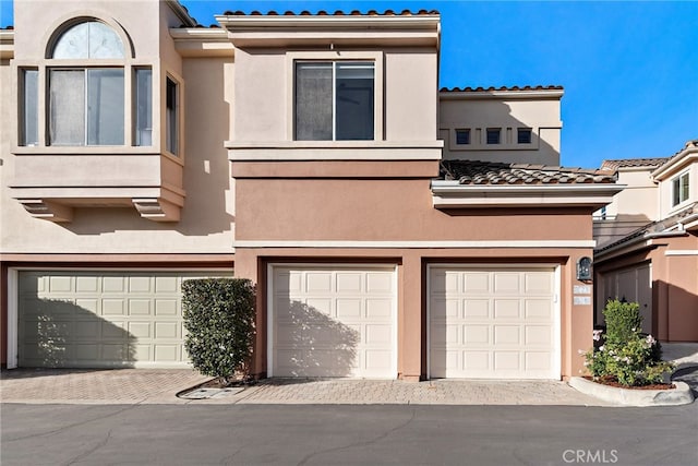 multi unit property featuring a garage, driveway, and stucco siding