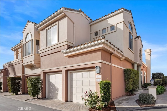 exterior space with a garage, a tiled roof, and stucco siding