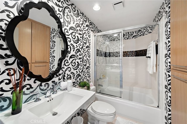 bathroom with enclosed tub / shower combo, a sink, visible vents, and toilet