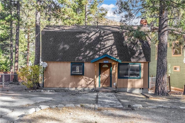 view of front facade featuring crawl space, roof with shingles, fence, and a chimney