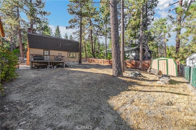 5768 Heath Creek Dr, Wrightwood, CA 92397 - view of yard with a storage unit, a wooden deck, a fenced backyard, and an outbuilding