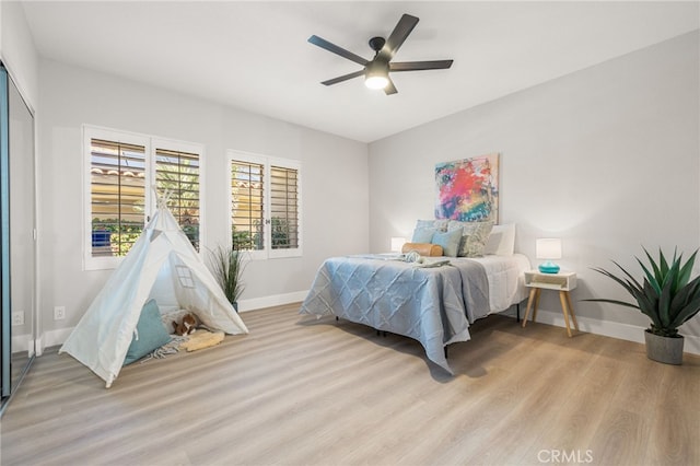 bedroom with light wood-style floors, baseboards, and a ceiling fan