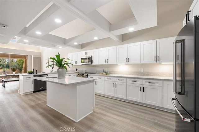 kitchen featuring white cabinets, a kitchen island, appliances with stainless steel finishes, a peninsula, and light wood-type flooring