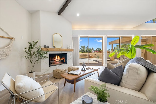 living room with lofted ceiling with beams, wood finished floors, a high end fireplace, and recessed lighting