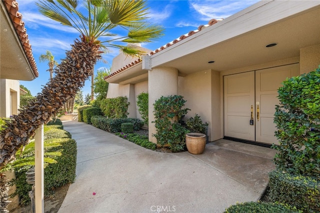 entrance to property featuring a tiled roof and stucco siding