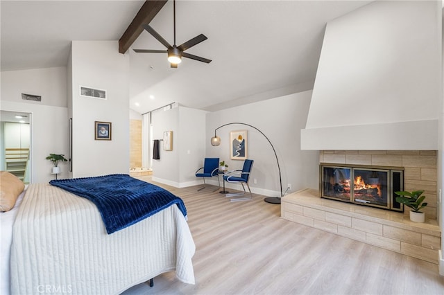 bedroom with baseboards, visible vents, a glass covered fireplace, light wood-type flooring, and beam ceiling