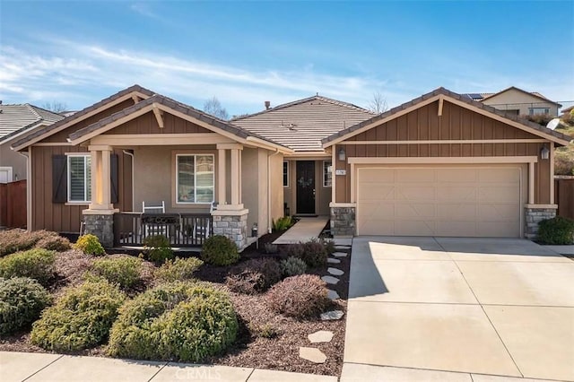 view of front of property with stone siding, covered porch, an attached garage, and concrete driveway