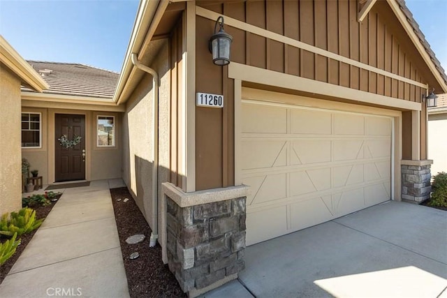 doorway to property featuring a garage, driveway, and board and batten siding